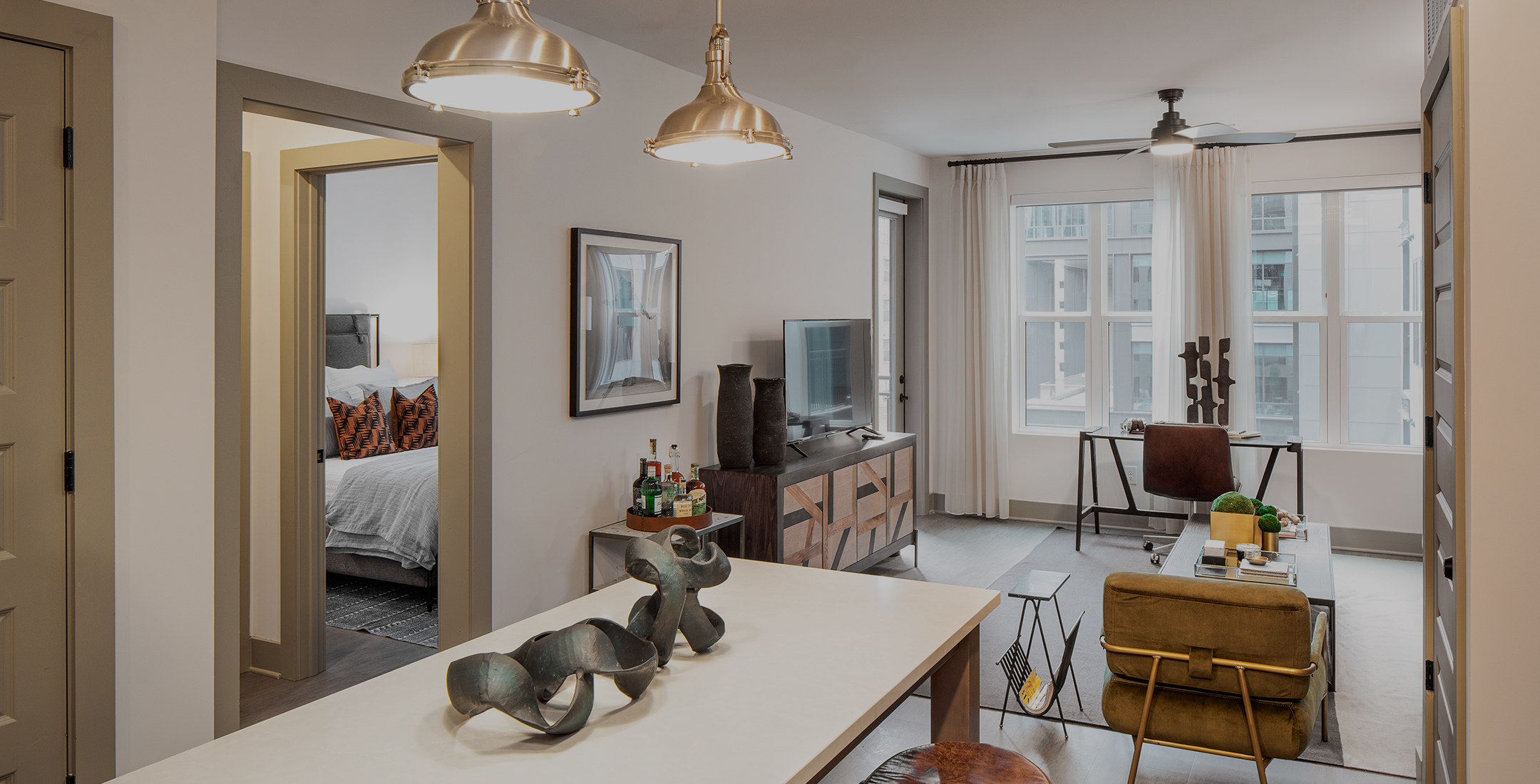 The Line model apartment with silver pendant lighting and living room view of the courtyard and bedroom